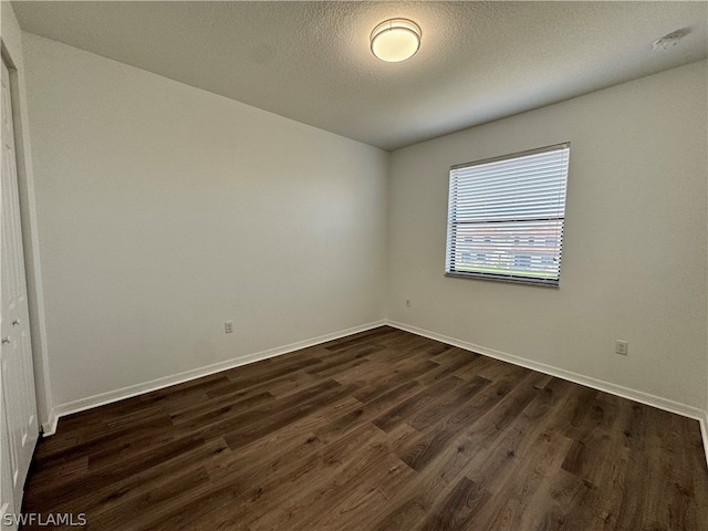 spare room with dark wood-type flooring and a textured ceiling