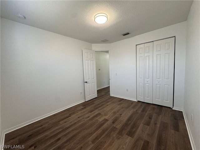 unfurnished bedroom with a closet, a textured ceiling, and dark hardwood / wood-style floors