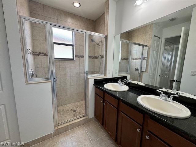 bathroom with tile floors, a shower with door, vanity with extensive cabinet space, and dual sinks