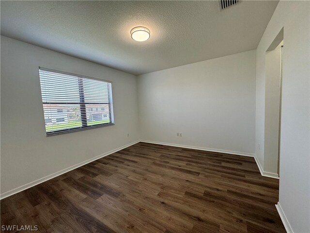 spare room featuring dark wood-type flooring and a textured ceiling