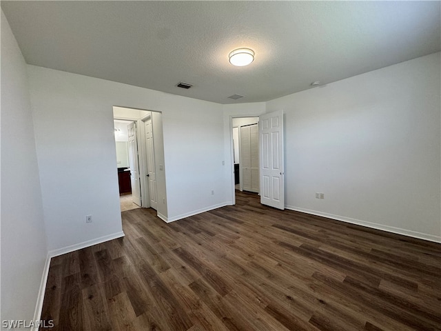 unfurnished bedroom with a closet, dark hardwood / wood-style flooring, and a textured ceiling