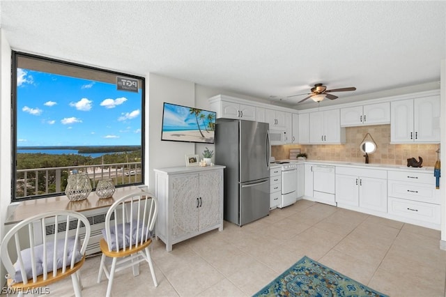 kitchen featuring light tile patterned floors, white appliances, backsplash, a textured ceiling, and white cabinets