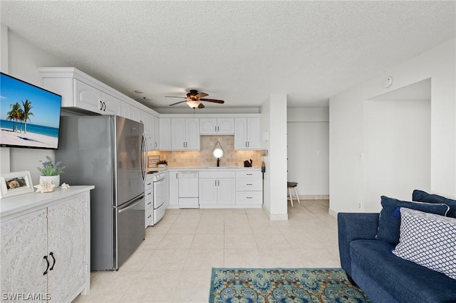 kitchen featuring tasteful backsplash, light tile patterned floors, stainless steel fridge, white dishwasher, and white cabinets