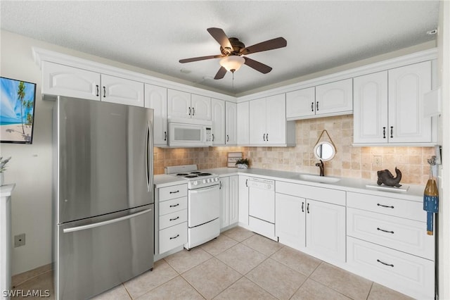 kitchen featuring sink, light tile patterned floors, white appliances, decorative backsplash, and white cabinets