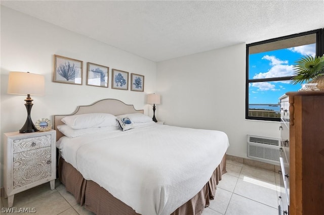 bedroom with a wall mounted air conditioner, a textured ceiling, and light tile patterned floors