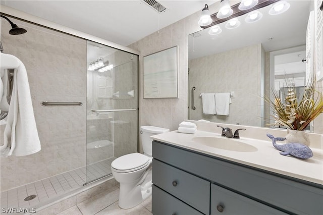 bathroom with tile patterned flooring, vanity, walk in shower, and toilet