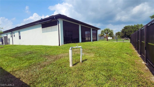 view of side of home featuring a sunroom and a yard