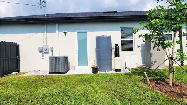 rear view of property with central AC unit and a yard