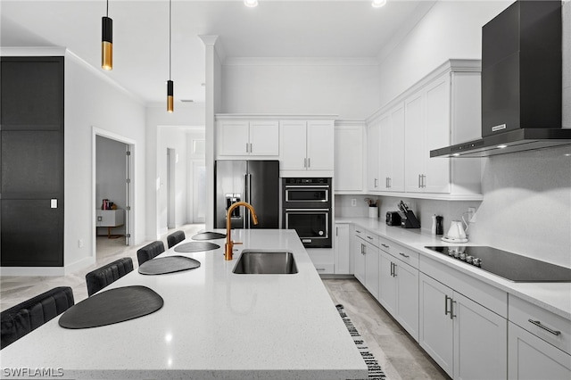 kitchen with wall chimney range hood, white cabinets, stainless steel appliances, and sink