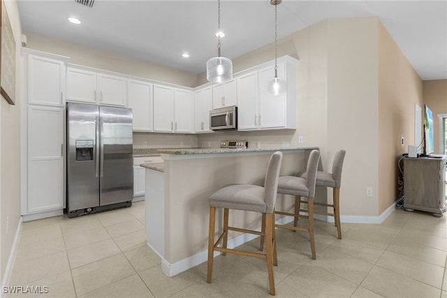 kitchen featuring light tile patterned floors, light stone counters, white cabinets, appliances with stainless steel finishes, and decorative light fixtures