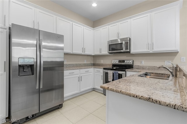 kitchen featuring appliances with stainless steel finishes, white cabinetry, a sink, and light tile patterned floors