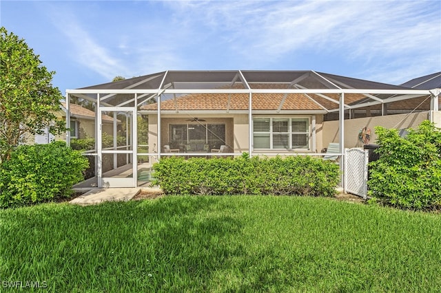 back of house with a lanai, a tile roof, a lawn, and stucco siding