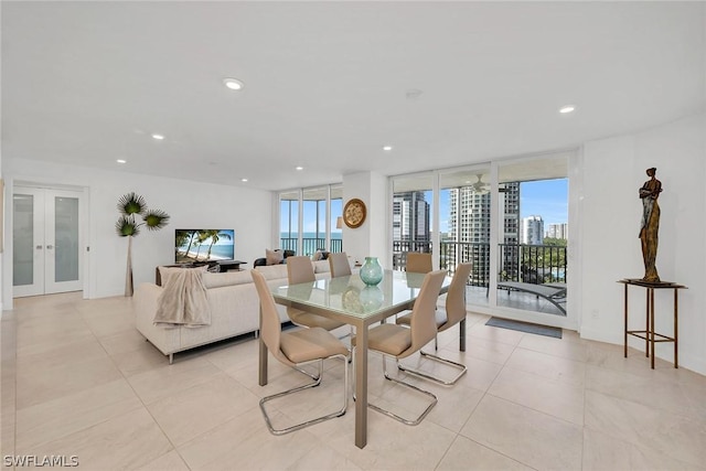 tiled dining area with plenty of natural light, a wall of windows, and french doors