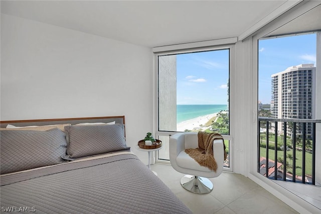 bedroom with expansive windows, a water view, a beach view, and multiple windows