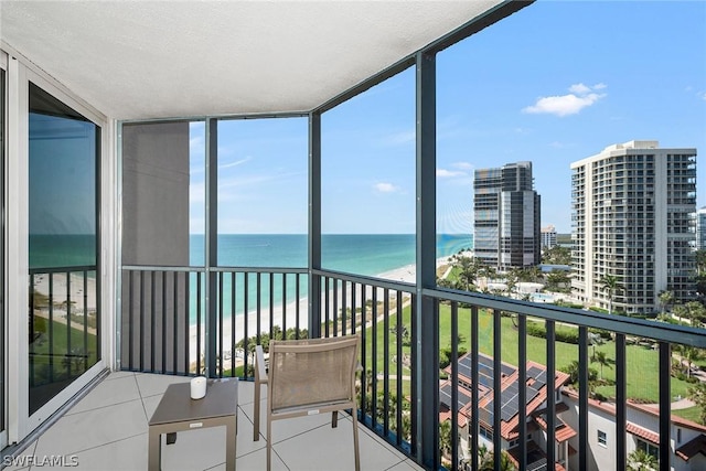 sunroom featuring a water view and a beach view