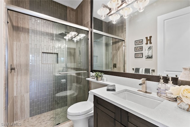 bathroom featuring vanity, a shower with door, and toilet