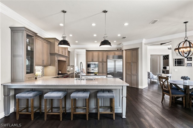 kitchen featuring pendant lighting, sink, a breakfast bar, kitchen peninsula, and built in fridge