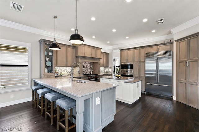 kitchen featuring sink, high end appliances, hanging light fixtures, kitchen peninsula, and light stone countertops