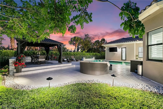 pool at dusk featuring a gazebo and a patio