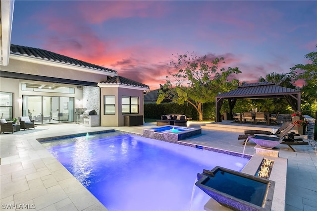 pool at dusk featuring a patio, an in ground hot tub, an outdoor living space with a fire pit, and a gazebo