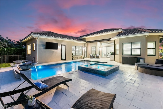 back of property with a swimming pool with hot tub, a patio, and pool water feature