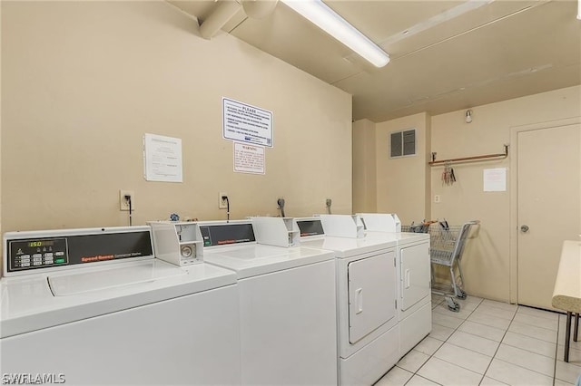 laundry area featuring electric dryer hookup, light tile floors, and washing machine and dryer