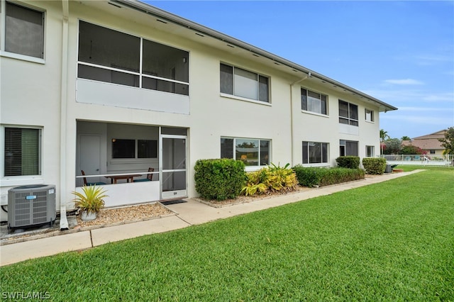 rear view of house featuring central AC unit and a yard