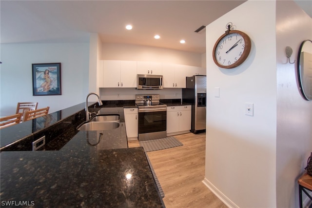 kitchen with light hardwood / wood-style flooring, dark stone countertops, sink, white cabinetry, and appliances with stainless steel finishes