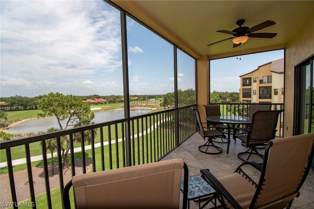 sunroom featuring ceiling fan and a water view