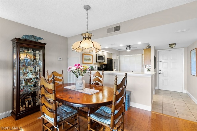 tiled dining space featuring a textured ceiling and ceiling fan