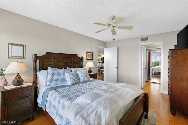 bedroom with a textured ceiling, ceiling fan, and hardwood / wood-style floors