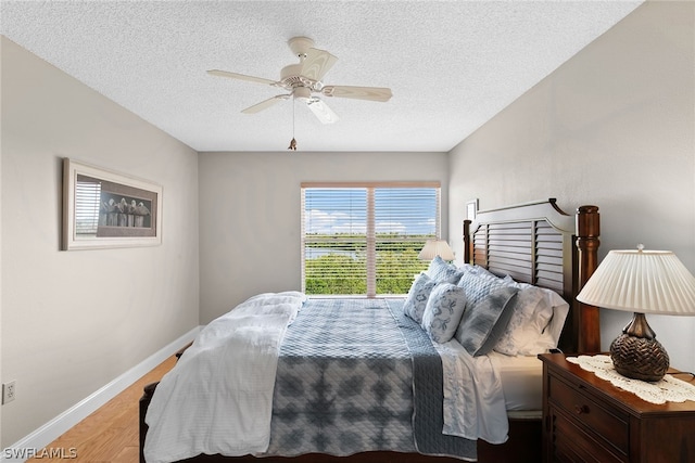 bedroom with ceiling fan, light hardwood / wood-style flooring, and a textured ceiling