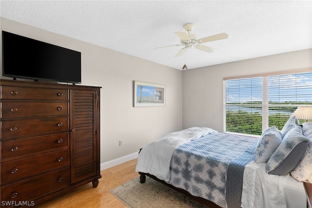 bedroom with ceiling fan, a textured ceiling, and light wood-type flooring