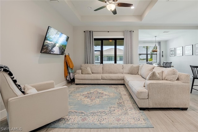 living room featuring ceiling fan, hardwood / wood-style flooring, and a tray ceiling