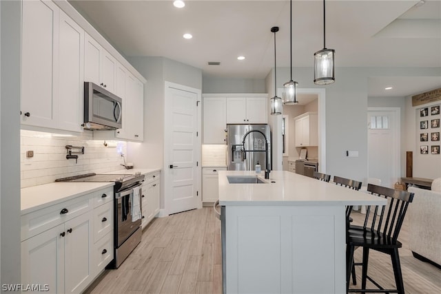 kitchen with stainless steel appliances, light hardwood / wood-style floors, tasteful backsplash, and white cabinets