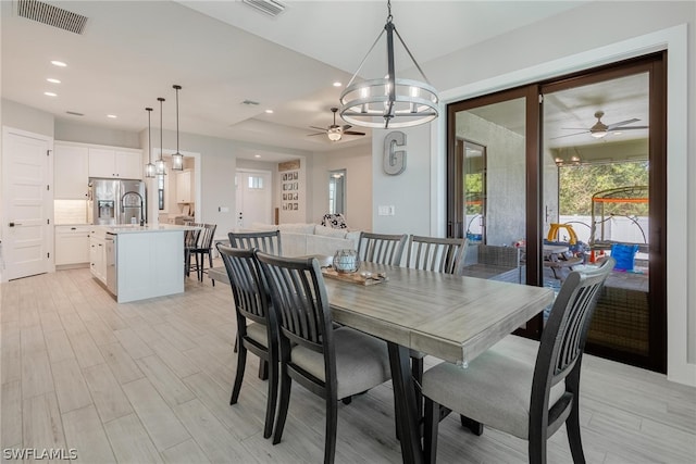 dining space featuring light hardwood / wood-style flooring and ceiling fan with notable chandelier