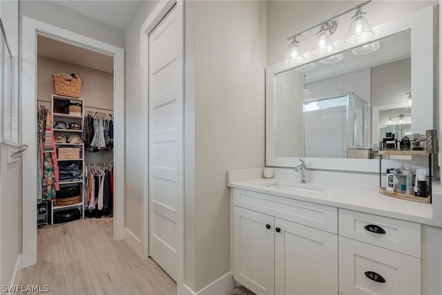 bathroom with walk in shower, wood-type flooring, and vanity