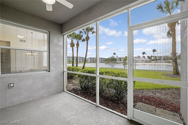 unfurnished sunroom with ceiling fan and a water view