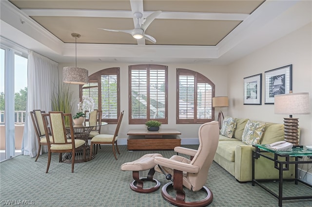 living room with ceiling fan, a tray ceiling, and carpet flooring