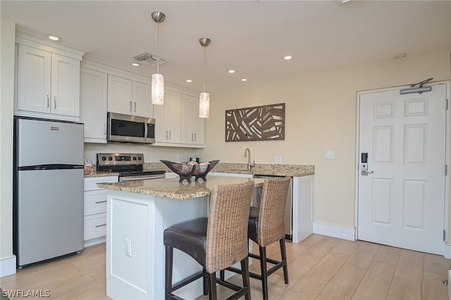 kitchen with light hardwood / wood-style flooring, decorative light fixtures, white cabinetry, and appliances with stainless steel finishes