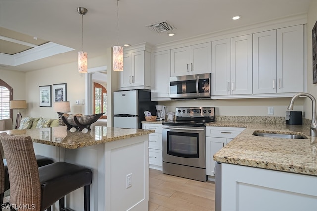 kitchen featuring light hardwood / wood-style floors, white cabinetry, hanging light fixtures, stainless steel appliances, and sink