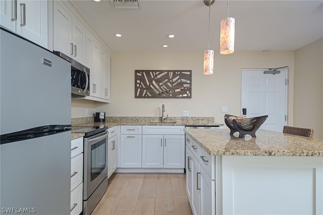 kitchen featuring white cabinetry, light stone countertops, appliances with stainless steel finishes, pendant lighting, and sink