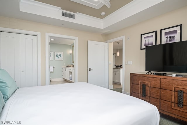 bedroom with a tray ceiling, ensuite bath, ceiling fan, and a closet