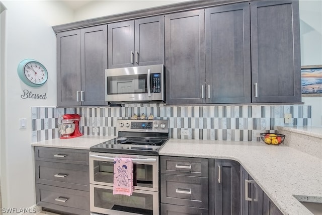 kitchen with stainless steel appliances, light stone countertops, and backsplash