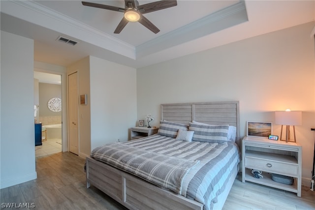 bedroom featuring light wood-type flooring, connected bathroom, a closet, ceiling fan, and a raised ceiling