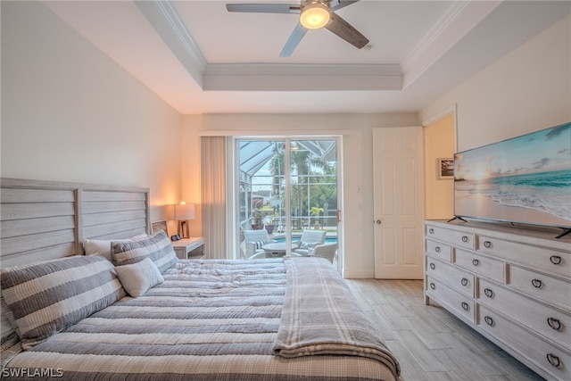 bedroom featuring light hardwood / wood-style floors, access to outside, ceiling fan, a tray ceiling, and ornamental molding