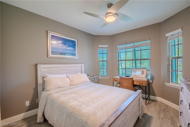 bedroom with multiple windows, ceiling fan, and light hardwood / wood-style flooring