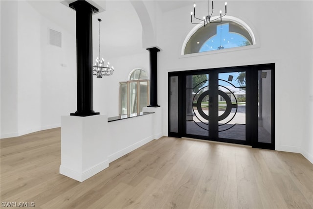 foyer entrance with a towering ceiling, light hardwood / wood-style floors, and a chandelier