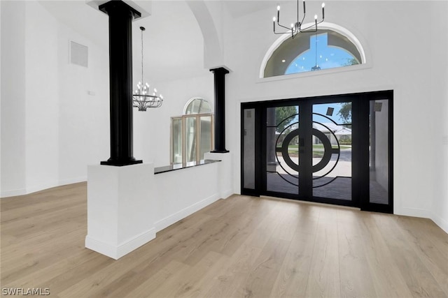 entryway with decorative columns, a notable chandelier, wood finished floors, baseboards, and visible vents