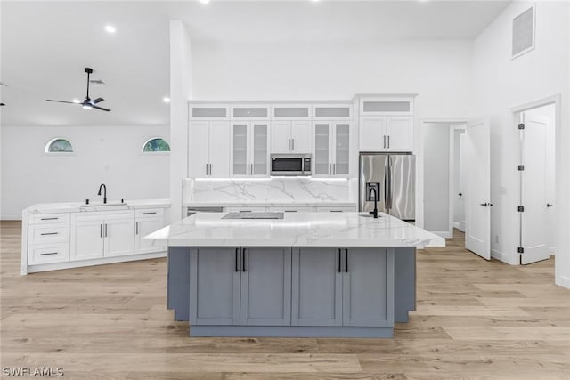 kitchen featuring sink, light stone counters, stainless steel appliances, a large island, and white cabinets